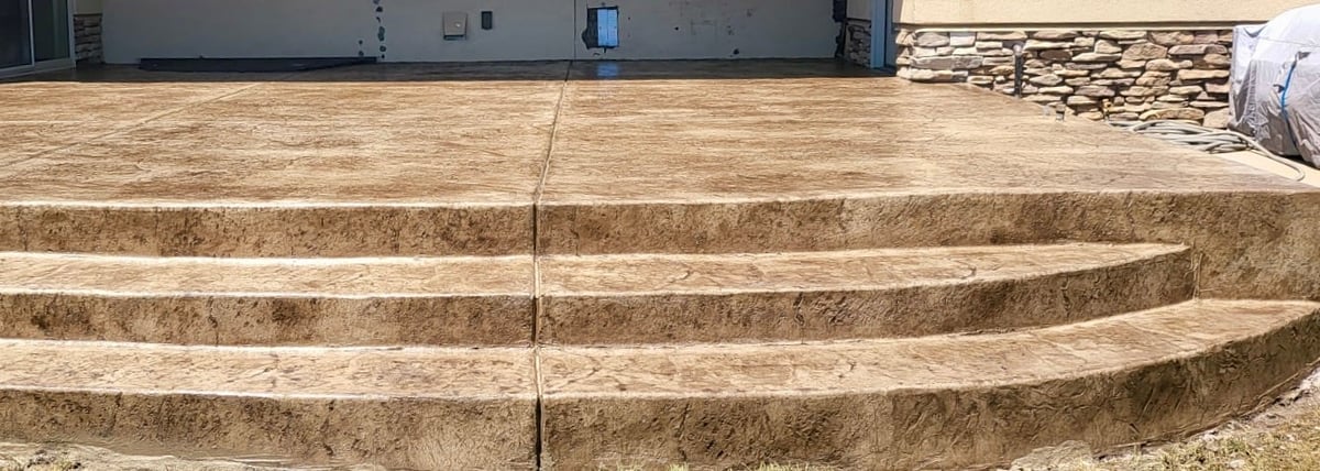 Curved concrete steps with brick facade leading upward to a level ground area with industrial buildings in background