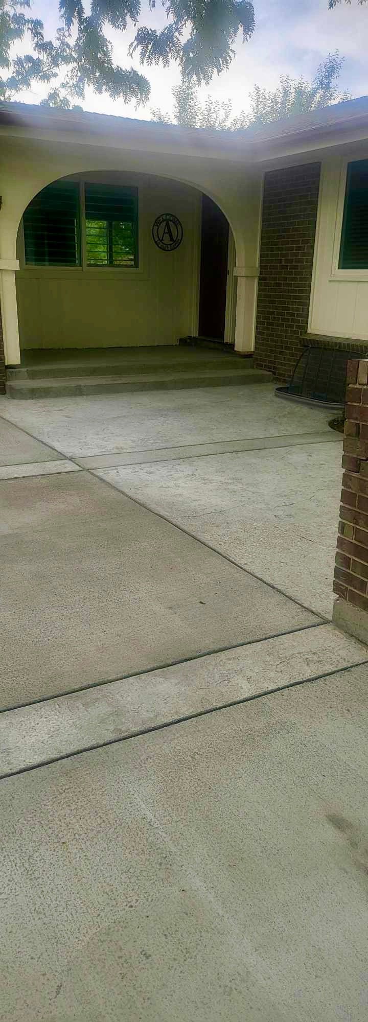 Covered patio area with yellow walls, arched entrance, green shutters, and brick pillars under a pergola with climbing vines